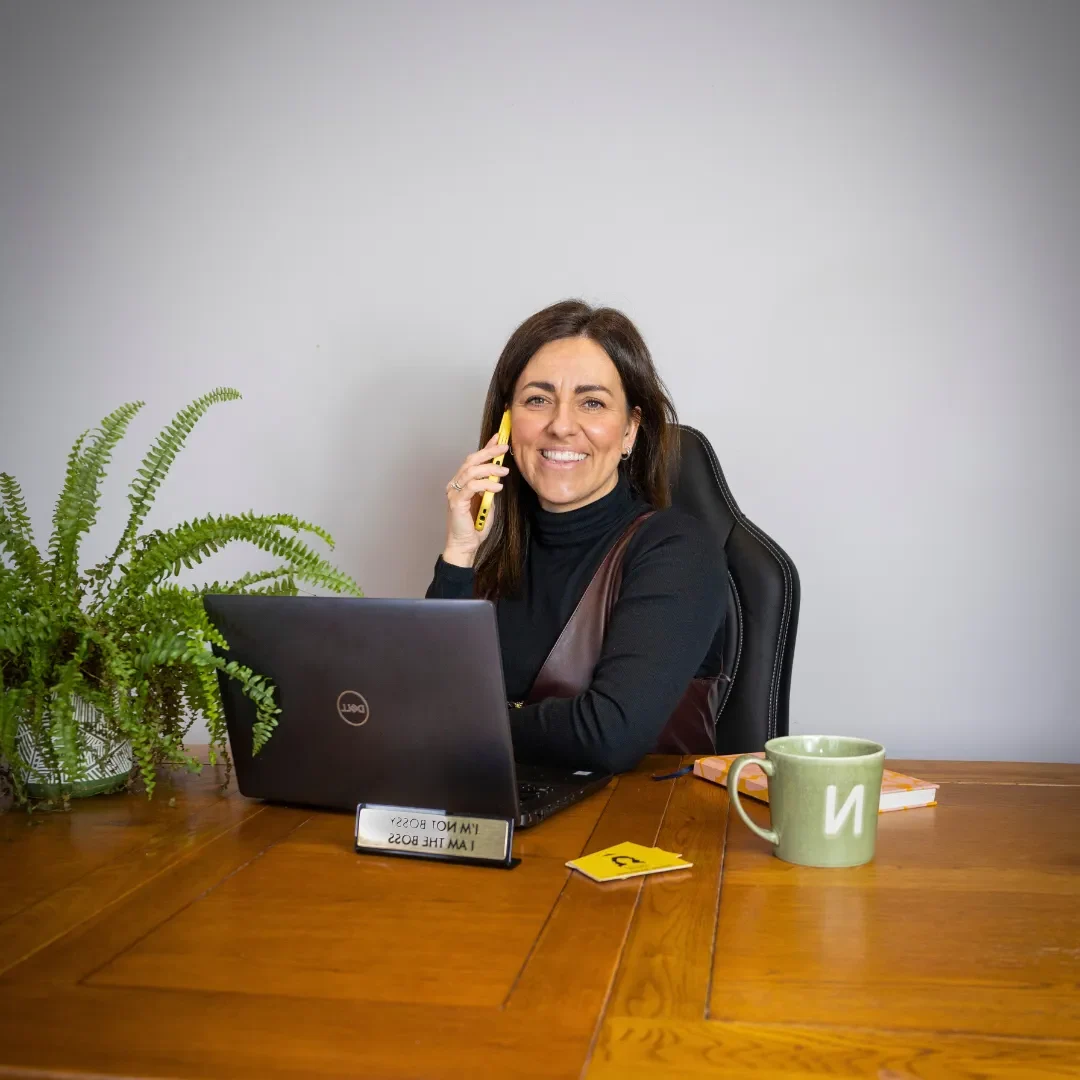 Natalie on the mobile behind a laptop