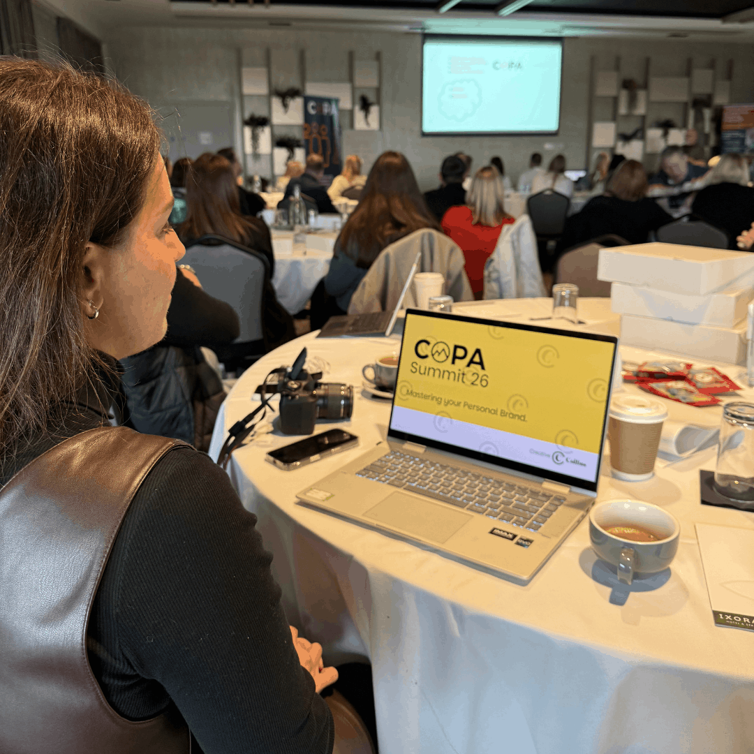 Natalie sitting down in a conference with the laptop screen showing COPA Summit 26