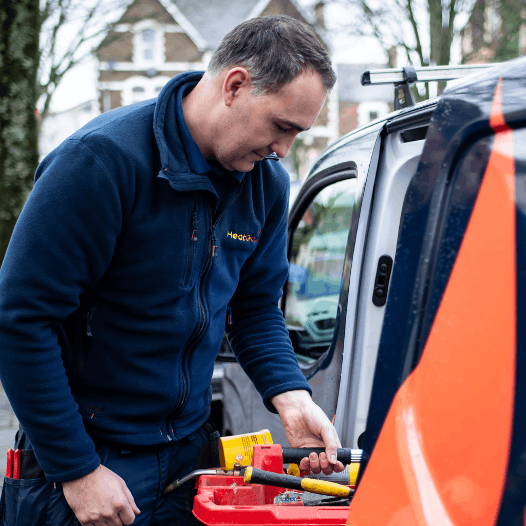 A plumber outside his van holding some equipment