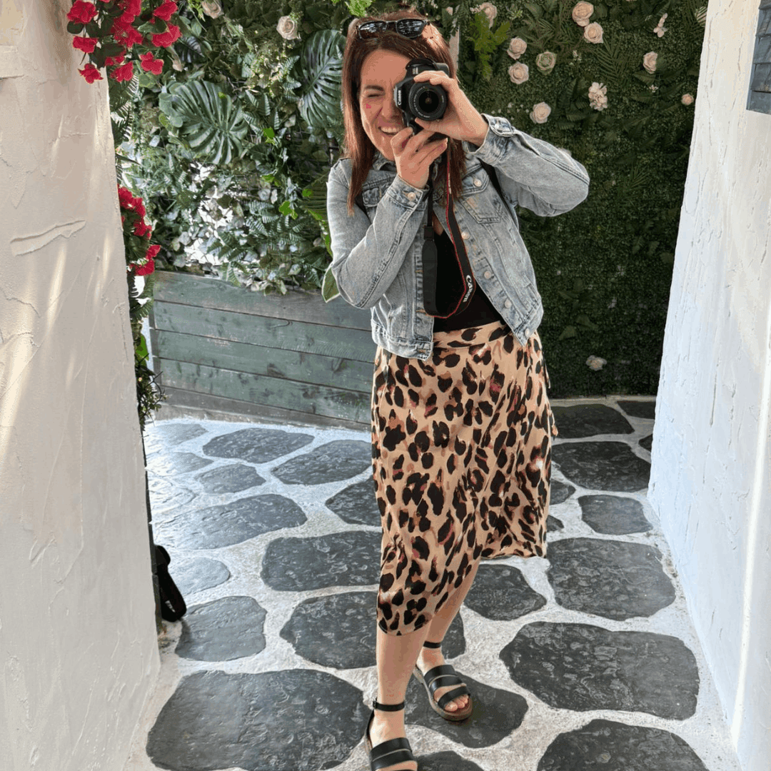 Natalie standing in a court yard holding a camera and ready to shoot