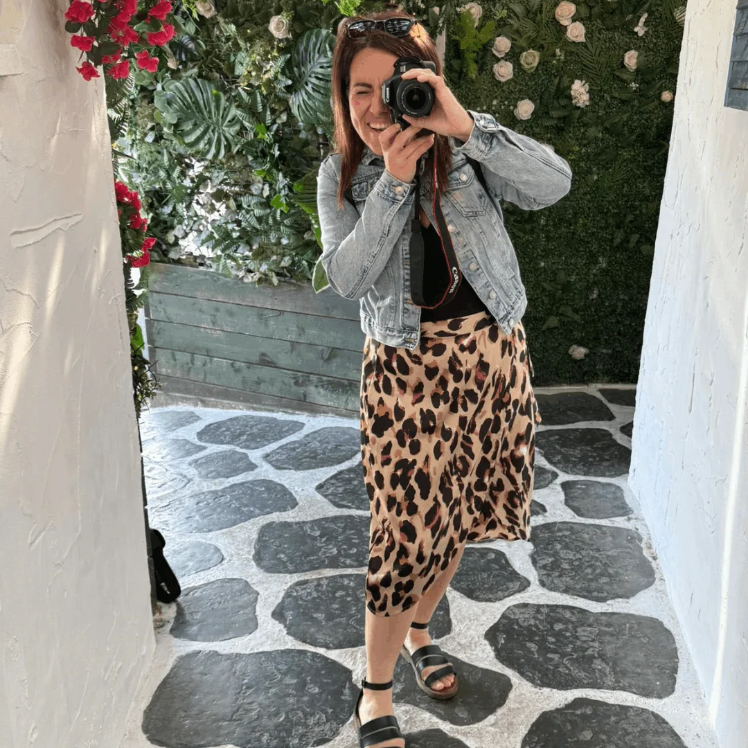 Natalie standing in a court yard holding a camera and ready to shoot